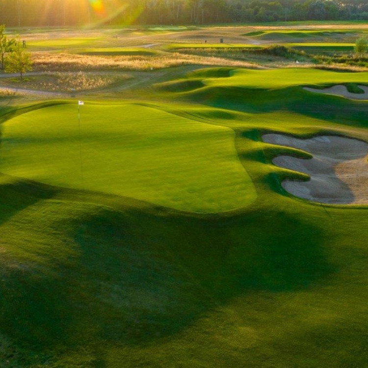 Zachód słońca nad greenami i bunkrami na polu golfowym Black Water Links