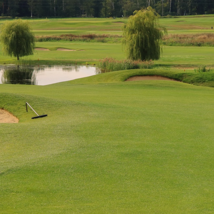 Zbliżenie na dwa bunkry i część stawu na polu golfowym